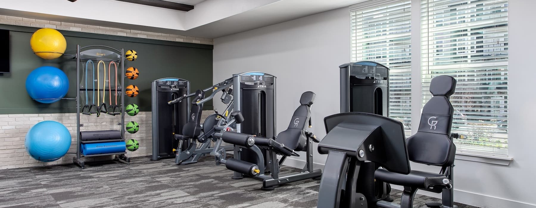 fitness center in a bright well-lit room showing plenty of equipment and modern decor in a large, spacious room